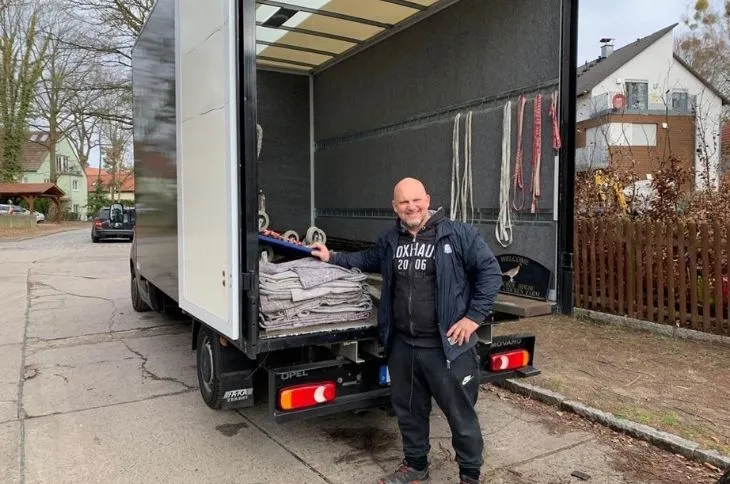 umzugshelfer steht laechelnd vor offenem umzugswagen